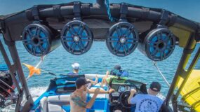 A family on a boat enjoying the water with speakers overhead