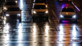 three cars driving down a street with the headlights facing the viewer