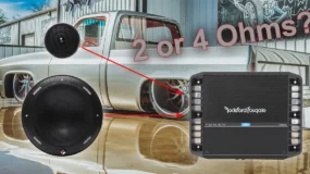 A white pickup truck in the background with speakers and an amplifier in the foreground